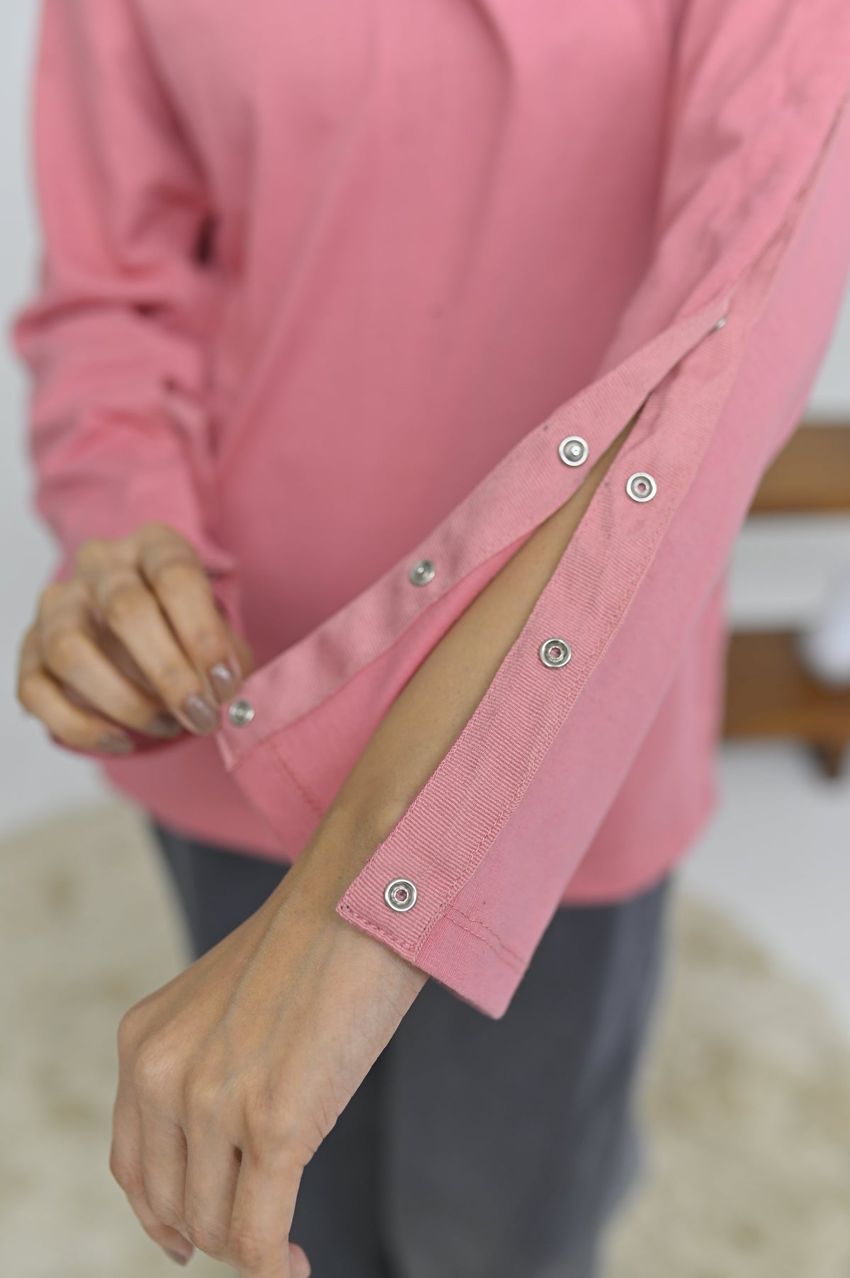Woman wearing an Inspired Comforts mastectomy recovery hoodie, getting dressed independently during recovery